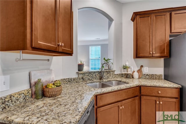 kitchen with sink, light stone counters, and stainless steel fridge