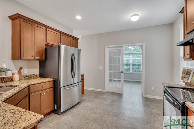 kitchen with french doors, appliances with stainless steel finishes, and light stone countertops