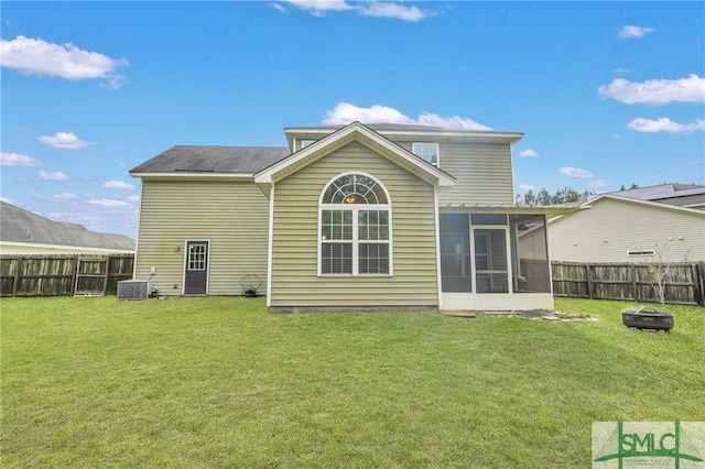 back of property with an outdoor fire pit, central air condition unit, a sunroom, and a yard