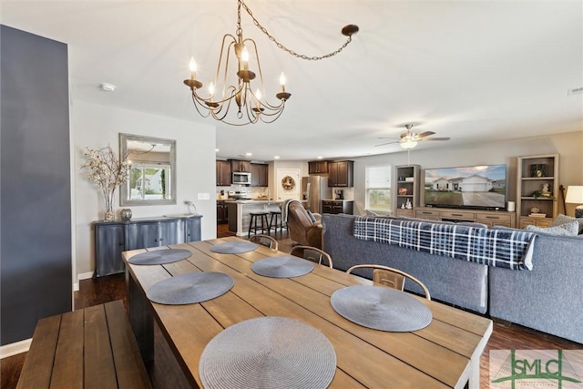 dining area featuring a healthy amount of sunlight, dark wood-type flooring, and ceiling fan with notable chandelier