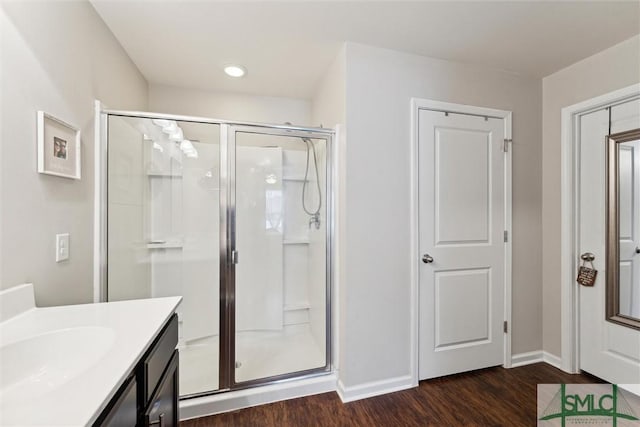 bathroom featuring hardwood / wood-style floors, a shower with door, and vanity