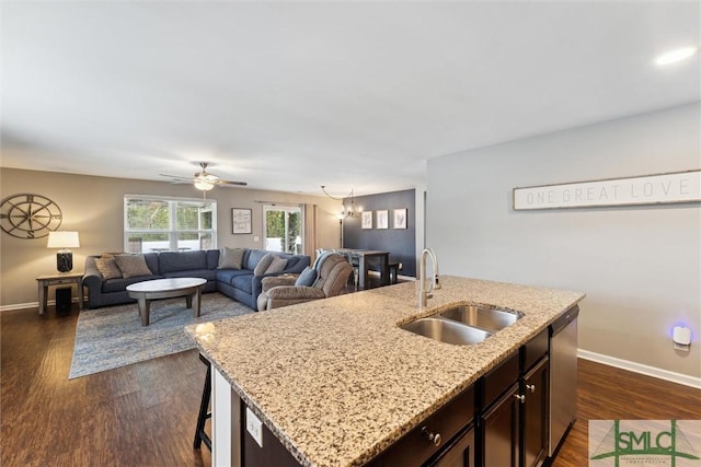 kitchen featuring ceiling fan with notable chandelier, sink, stainless steel dishwasher, a center island with sink, and dark brown cabinets