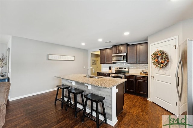 kitchen with a breakfast bar, decorative backsplash, sink, an island with sink, and stainless steel appliances