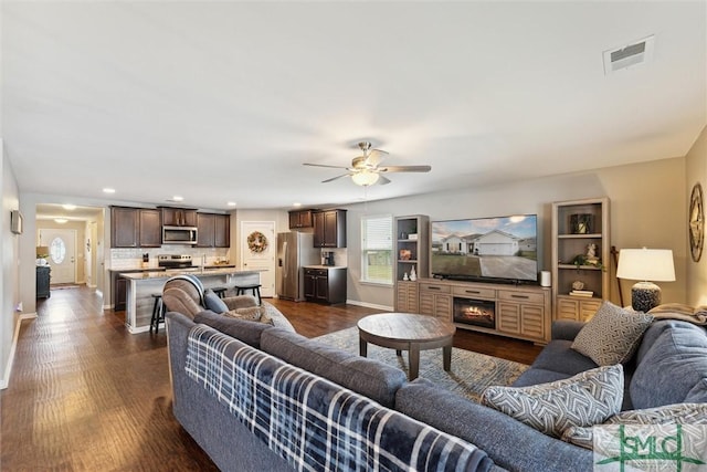 living room featuring ceiling fan and dark wood-type flooring