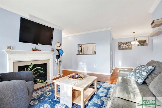 living room with a tiled fireplace, wood-type flooring, and ornamental molding