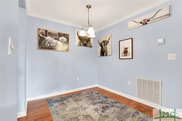 dining area with hardwood / wood-style floors, a chandelier, and crown molding