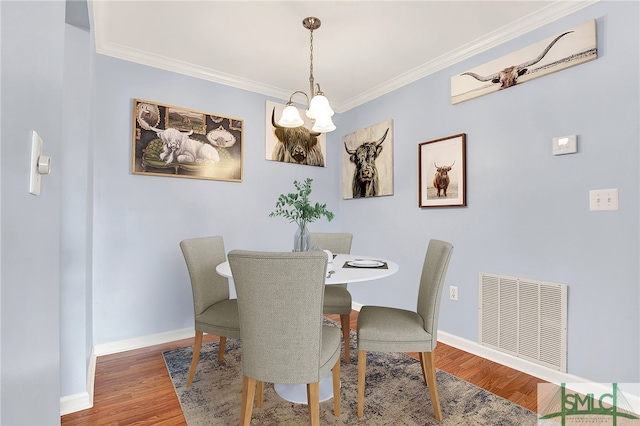 dining space featuring ornamental molding, hardwood / wood-style floors, and a notable chandelier