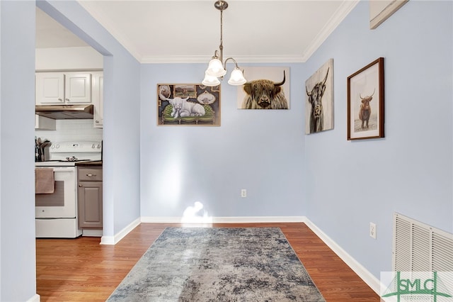 dining area with hardwood / wood-style floors, a notable chandelier, and ornamental molding