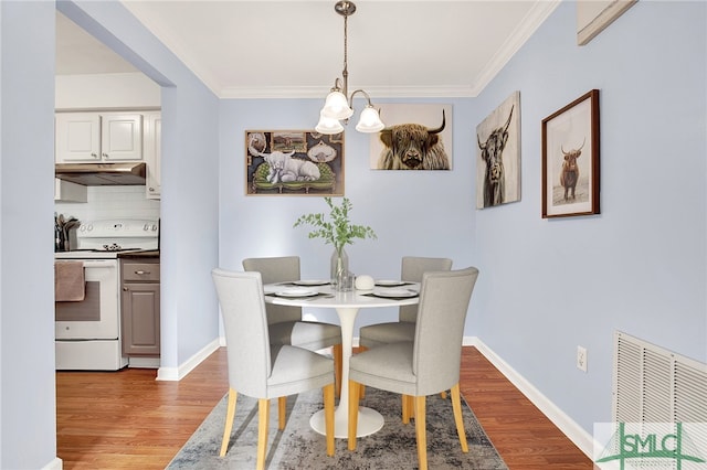 dining area featuring light wood-type flooring, an inviting chandelier, and crown molding