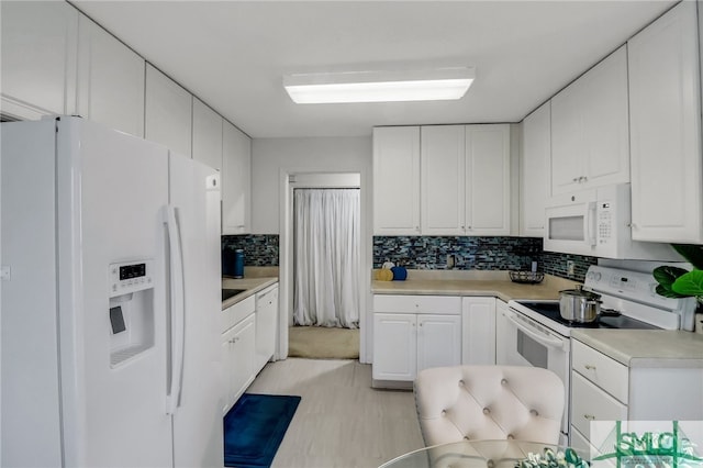 kitchen with white cabinets, decorative backsplash, light hardwood / wood-style flooring, and white appliances