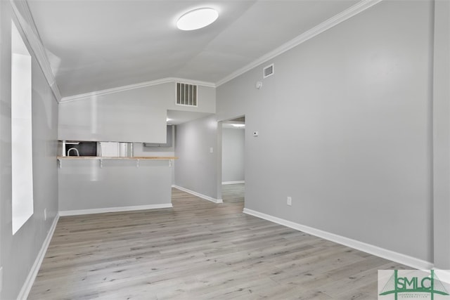 unfurnished living room featuring light hardwood / wood-style flooring, vaulted ceiling, and crown molding