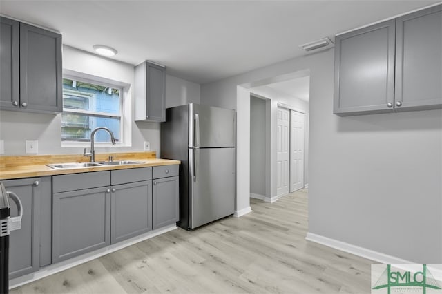 kitchen featuring light hardwood / wood-style floors, stainless steel fridge, gray cabinetry, and sink