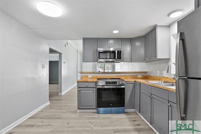 kitchen featuring gray cabinets, light hardwood / wood-style flooring, sink, and stainless steel appliances