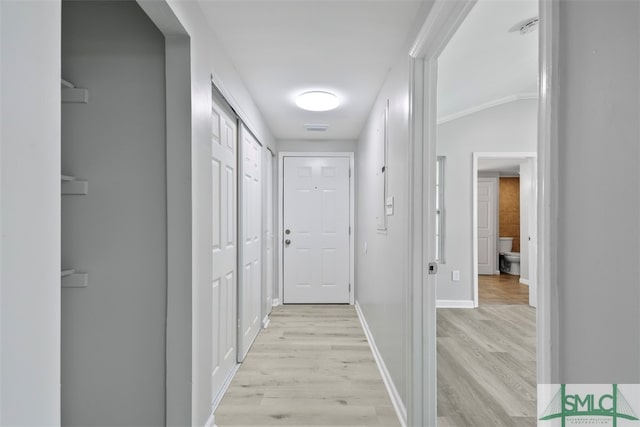 hall with crown molding, light wood-type flooring, and lofted ceiling