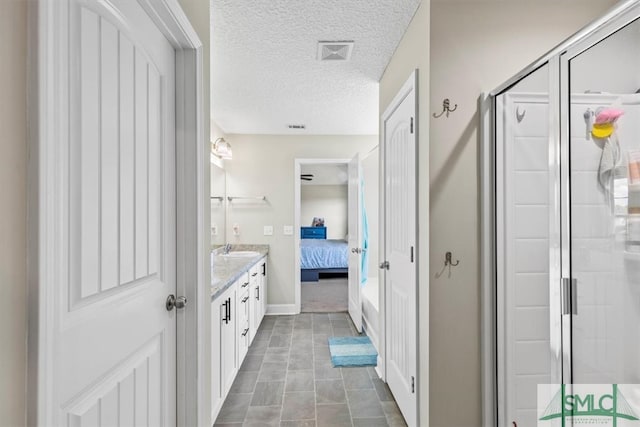 bathroom featuring vanity, a textured ceiling, and a shower with door