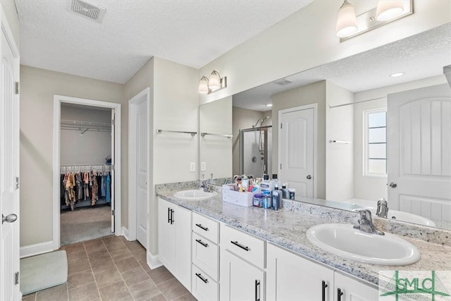 bathroom featuring vanity, an enclosed shower, and a textured ceiling