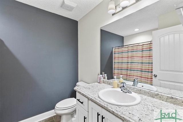 bathroom with toilet, vanity, a textured ceiling, and tile patterned floors