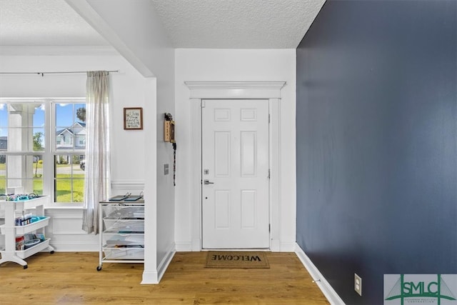 foyer entrance with light wood-type flooring, a wealth of natural light, and a textured ceiling