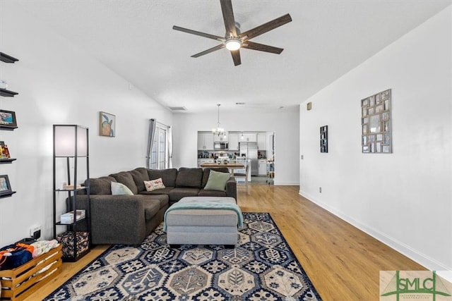 living room featuring light hardwood / wood-style floors and ceiling fan with notable chandelier