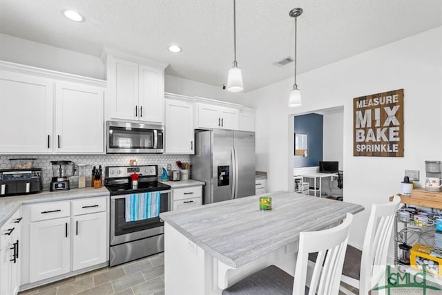 kitchen with white cabinets, a kitchen breakfast bar, pendant lighting, and appliances with stainless steel finishes