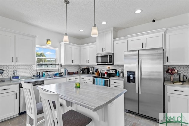 kitchen featuring stainless steel appliances, white cabinetry, and pendant lighting