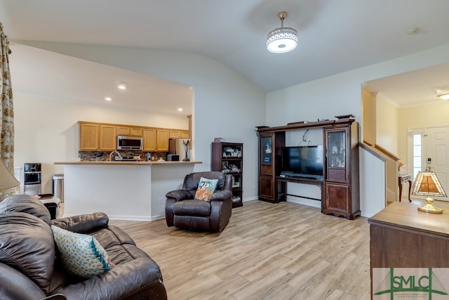 living room with light wood-type flooring, ornamental molding, and vaulted ceiling