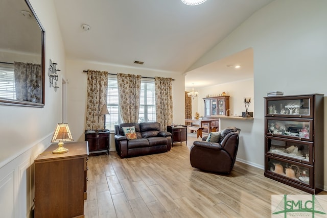 living area with vaulted ceiling, light wood-style flooring, visible vents, and a chandelier