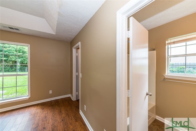 hallway with a textured ceiling, a wealth of natural light, and dark wood-type flooring