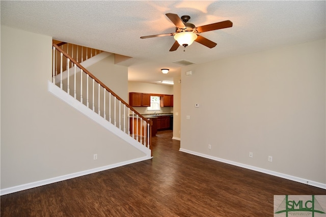 unfurnished living room with a textured ceiling, dark hardwood / wood-style floors, and ceiling fan