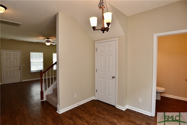 entrance foyer featuring a textured ceiling, ceiling fan with notable chandelier, dark hardwood / wood-style floors, and vaulted ceiling