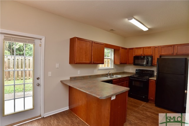 kitchen with plenty of natural light, black appliances, sink, and dark wood-type flooring