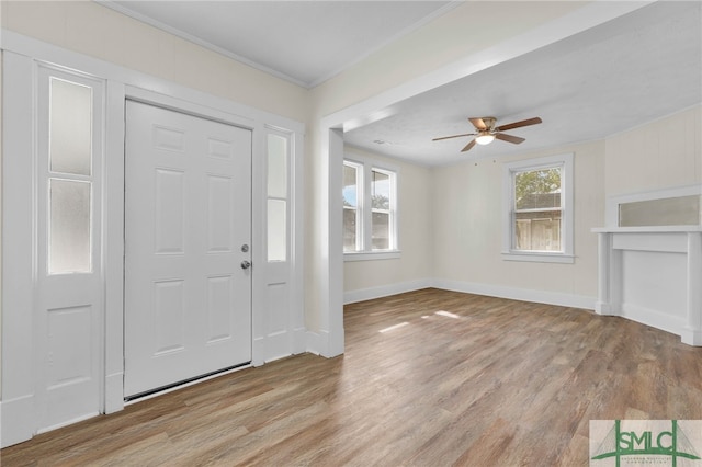 entrance foyer featuring light wood-type flooring, ceiling fan, and crown molding