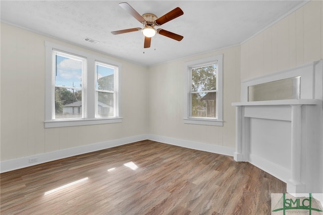 empty room with crown molding, wood-type flooring, a healthy amount of sunlight, and ceiling fan