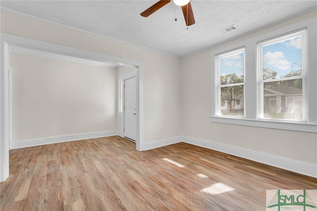 spare room featuring ornamental molding, light wood-type flooring, a textured ceiling, and ceiling fan