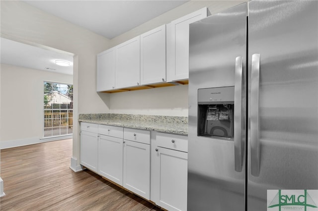 kitchen featuring light stone countertops, stainless steel refrigerator with ice dispenser, white cabinetry, and light wood-type flooring