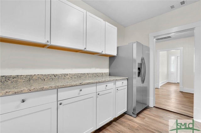 kitchen with white cabinets, stainless steel refrigerator with ice dispenser, light hardwood / wood-style floors, and light stone countertops