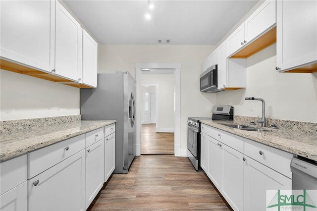 kitchen featuring light stone counters, white cabinetry, appliances with stainless steel finishes, sink, and light hardwood / wood-style floors