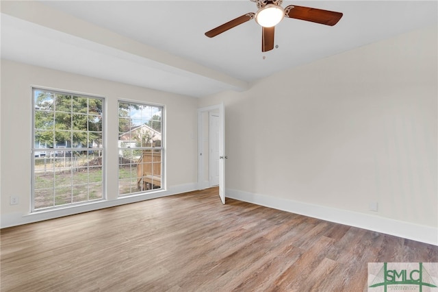 unfurnished room featuring ceiling fan, light hardwood / wood-style floors, and beam ceiling