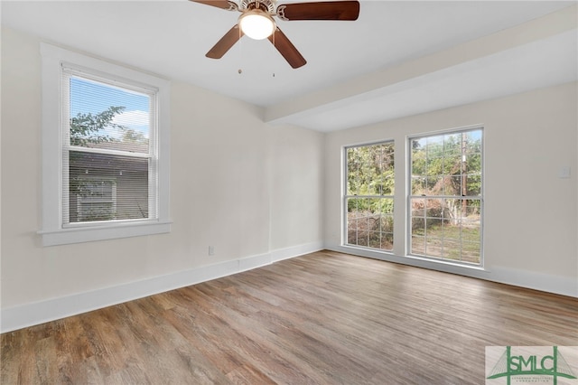 unfurnished room with ceiling fan, wood-type flooring, plenty of natural light, and beam ceiling