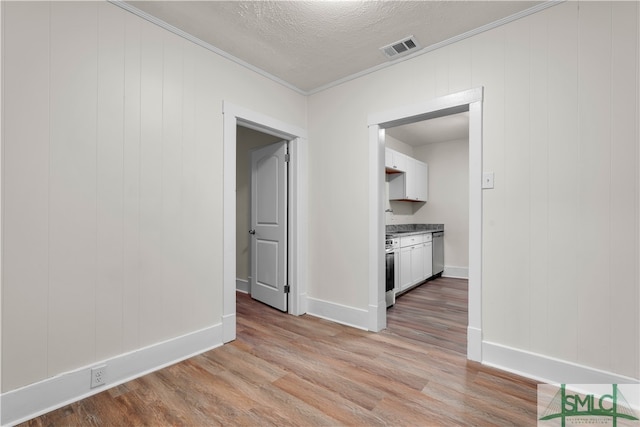 interior space with ornamental molding, light hardwood / wood-style floors, and a textured ceiling