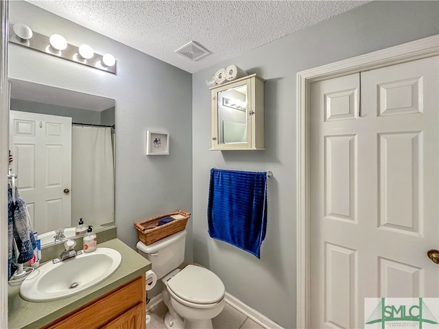 bathroom featuring toilet, vanity, a textured ceiling, and tile patterned floors