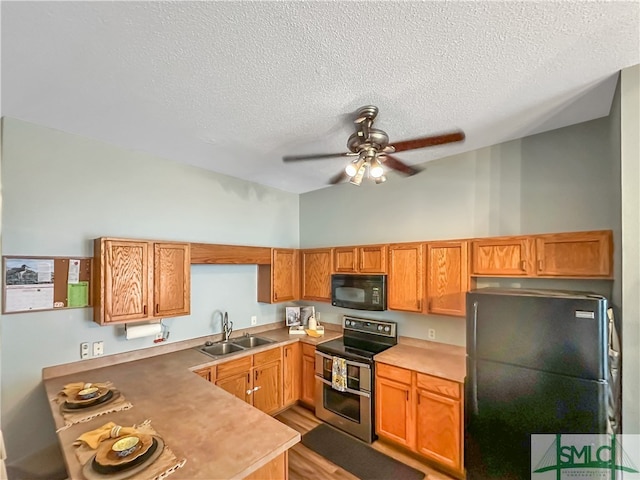 kitchen featuring light hardwood / wood-style floors, a textured ceiling, sink, and black appliances