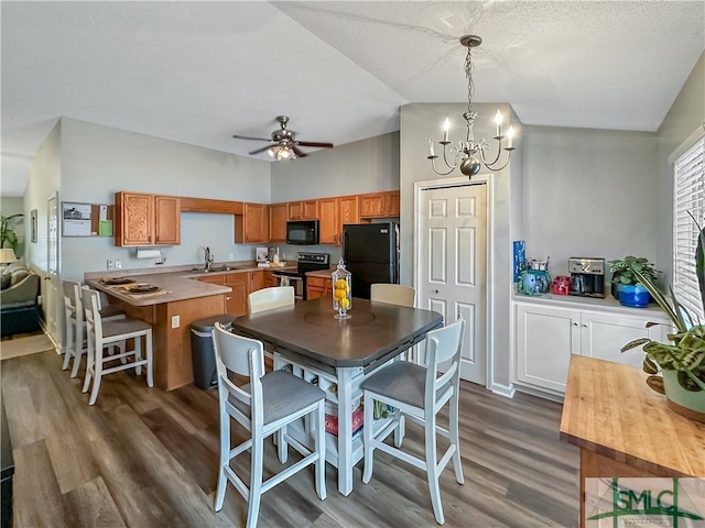 dining area featuring ceiling fan with notable chandelier, dark hardwood / wood-style flooring, vaulted ceiling, a textured ceiling, and sink