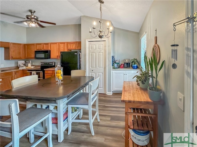 kitchen with pendant lighting, black appliances, dark hardwood / wood-style floors, and vaulted ceiling