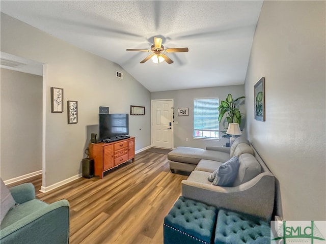 living room featuring a textured ceiling, wood-type flooring, ceiling fan, and vaulted ceiling