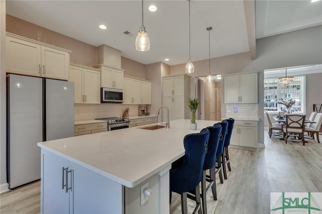 kitchen featuring decorative light fixtures, sink, a center island with sink, and stainless steel appliances