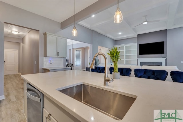 kitchen with pendant lighting, light hardwood / wood-style floors, sink, and dishwasher