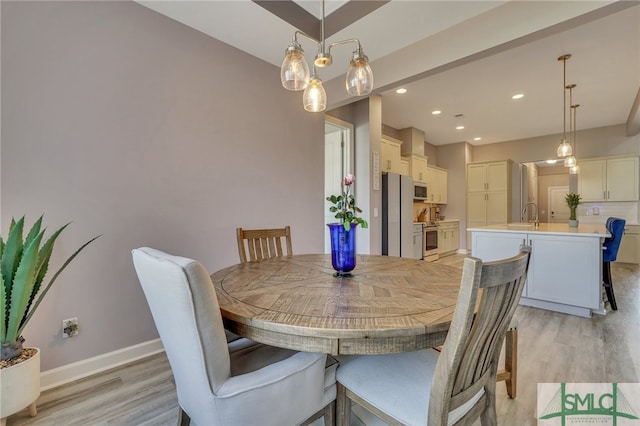 dining space featuring sink, an inviting chandelier, and light hardwood / wood-style floors