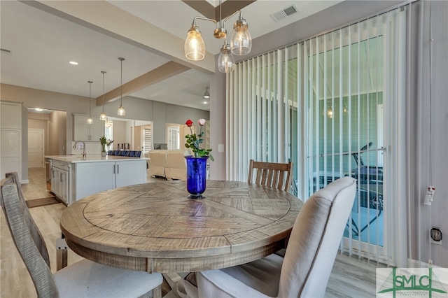 dining space featuring light wood-type flooring, a chandelier, and sink