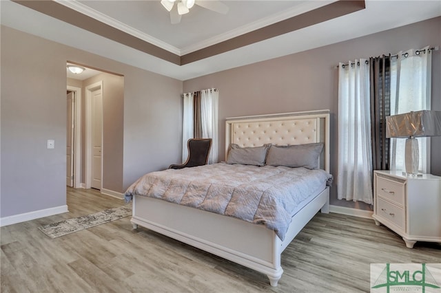 bedroom featuring light hardwood / wood-style floors, a raised ceiling, ceiling fan, and crown molding